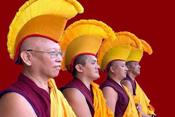 Four Tibetan monks dressed in traditional garments.